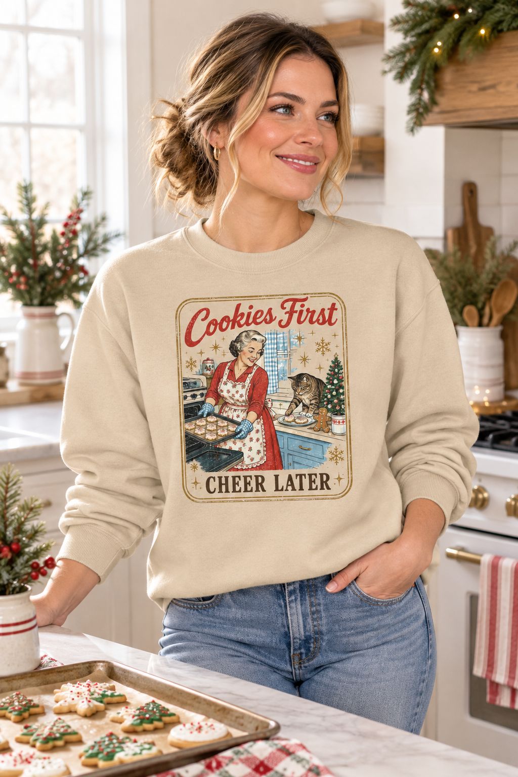 Woman wearing the Cookies First Cheer Later sweatshirt in a kitchen with Christmas cookies
